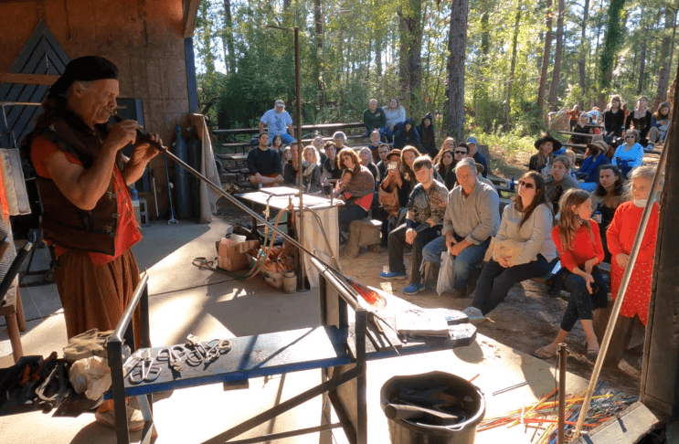 Audience watching Mark Haller, as he crafts blown glass using the off-hand technique