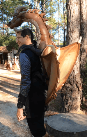 Side view of Cosplayer with inflatable dragon on his back.